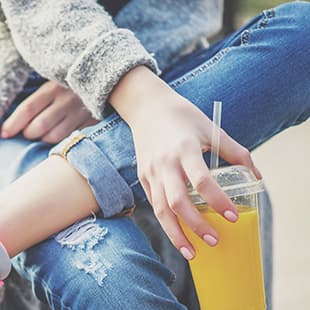 Image:  Woman with legs crossed holding a drink.